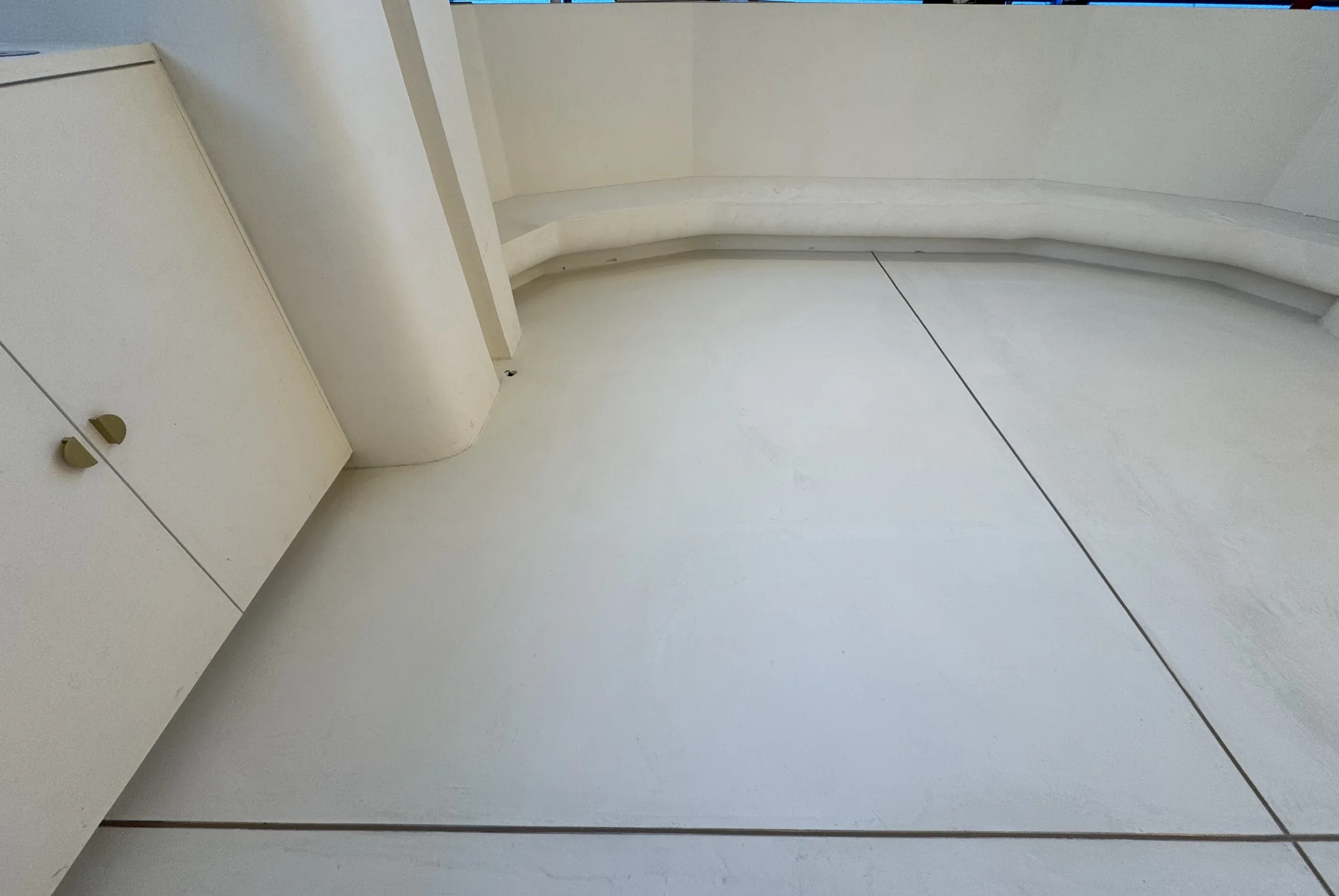 Seamless pale microcement floor with a curved wall detail