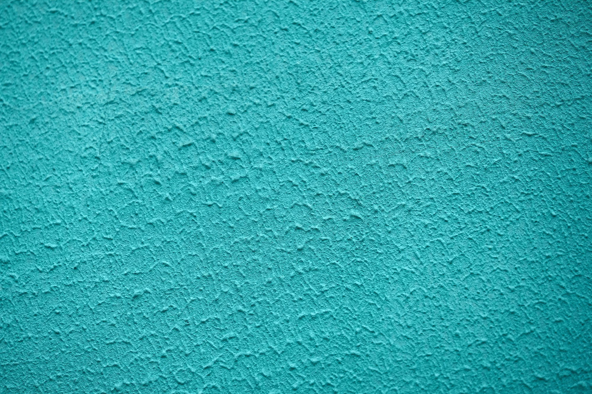 Turquoise textured plaster surface in raking light