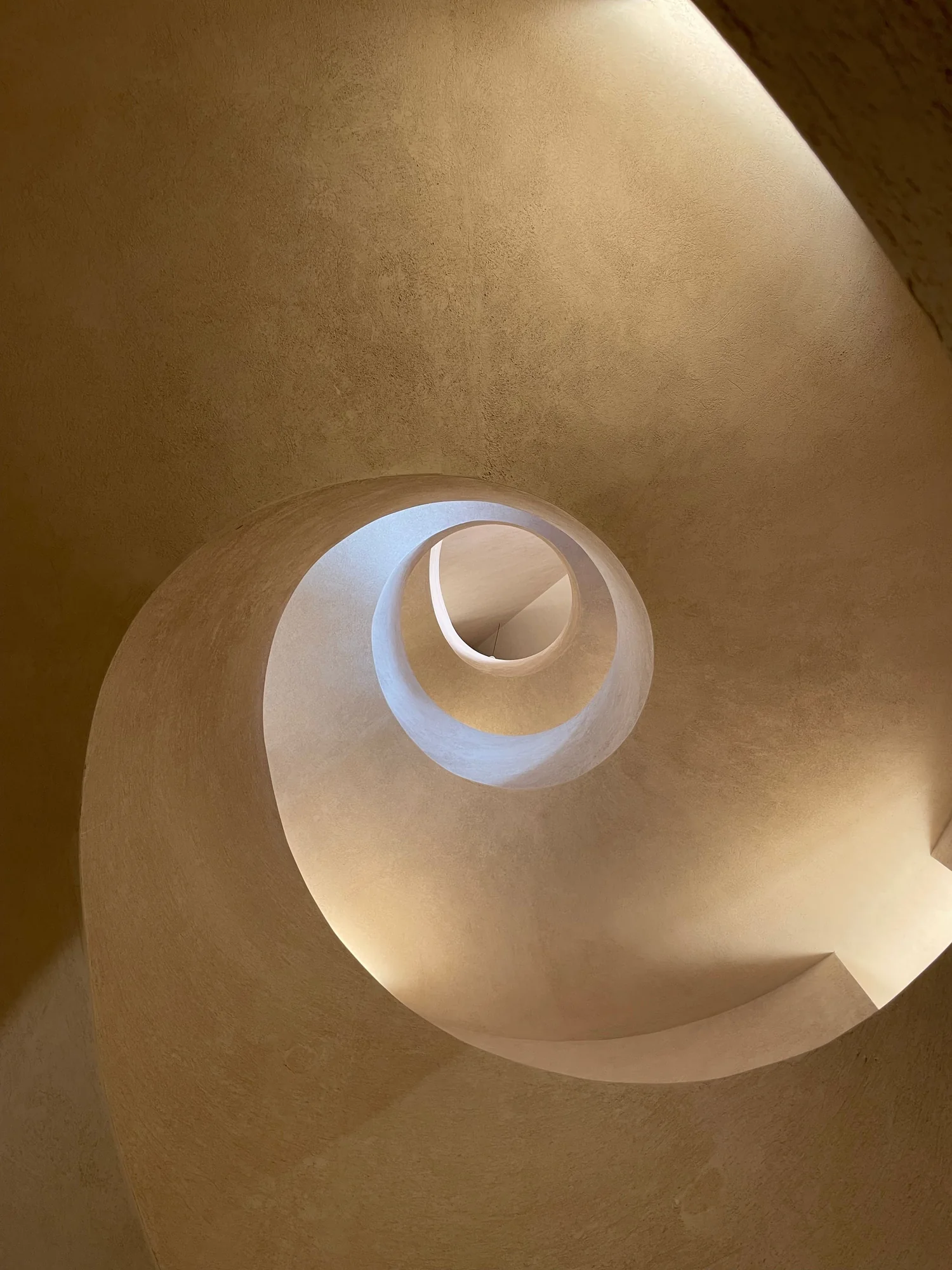 Honey bronze plaster sculpted around a spiral stairwell